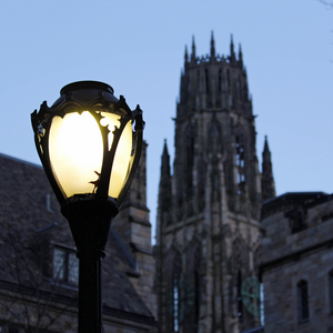 A lamp shines in the darkness as the sun sets on Yale's campus