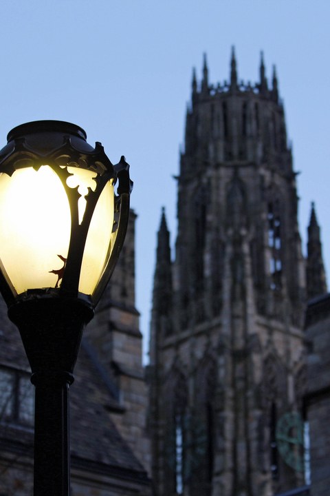 A lamp shines in the darkness as the sun sets on Yale's campus